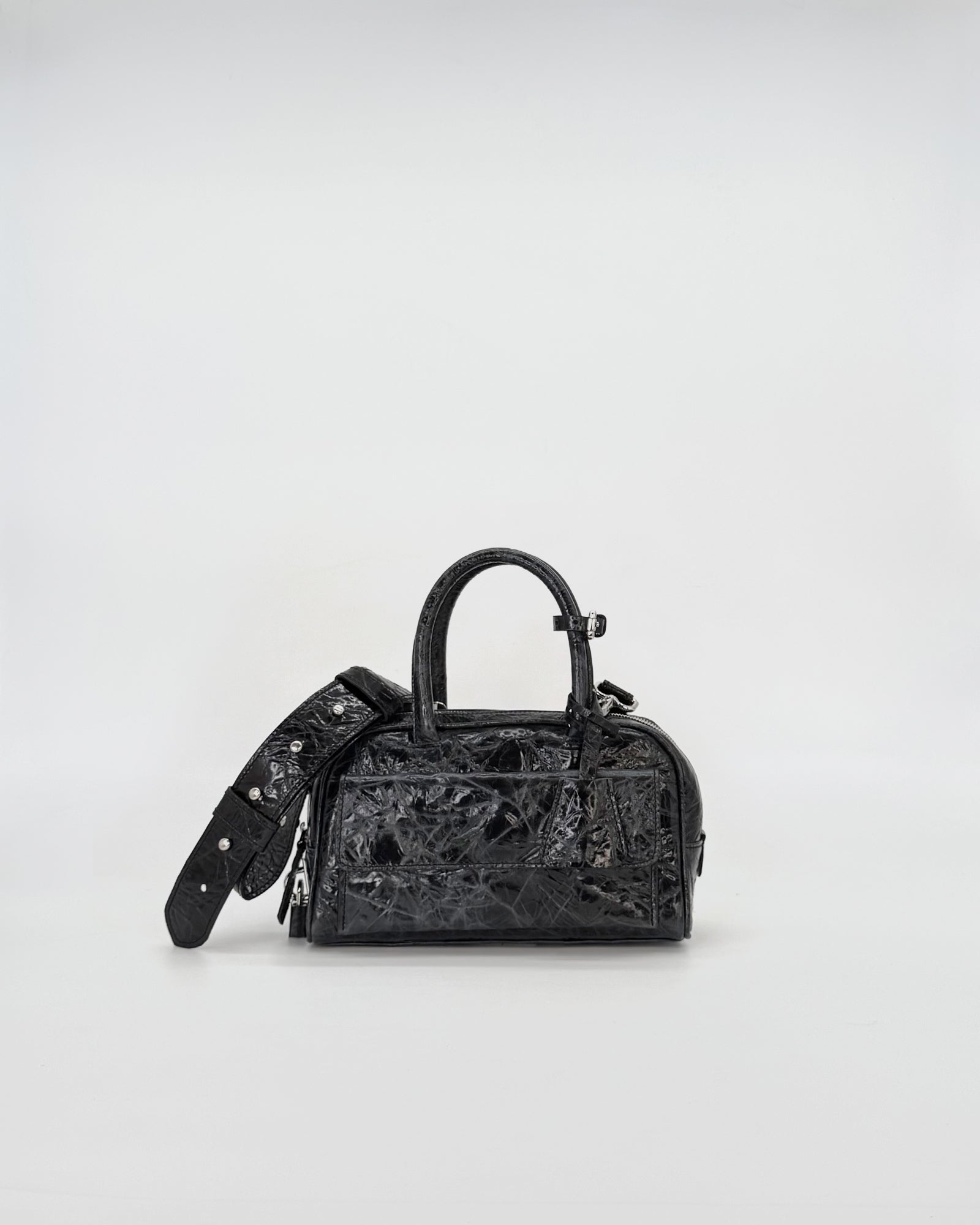 Zoe Mini Vitello Strizzato black handbag with an adjustable strap on a light background.